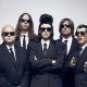 Puscifer Are Suited Up in ‘Fake Affront’ Video