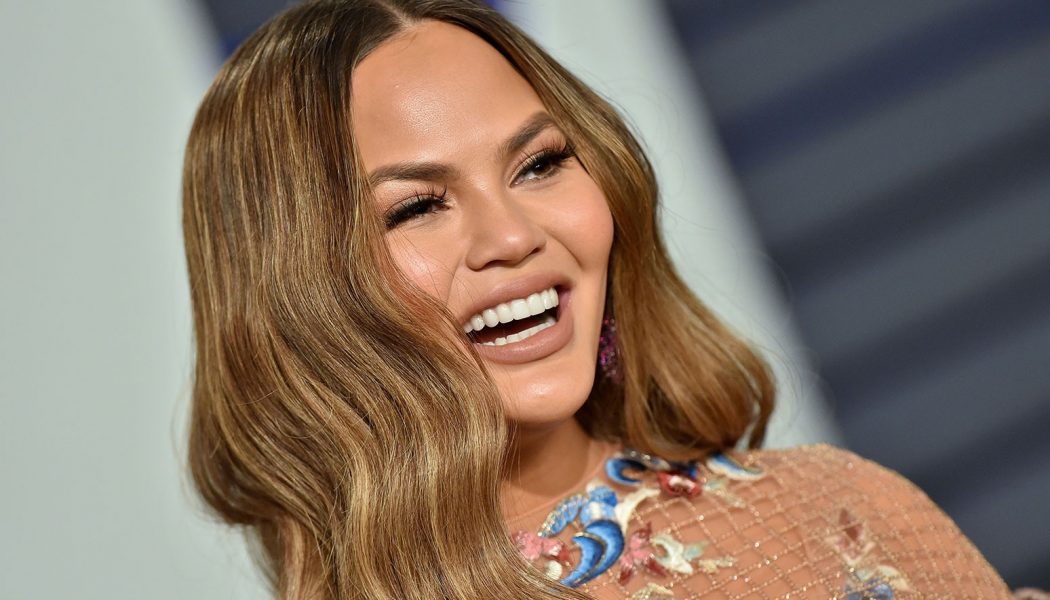 Chrissy Teigen Channels Cher’s ’90s Workout Videos For ‘The Best 38 Minutes of Fat-Burning Fun’