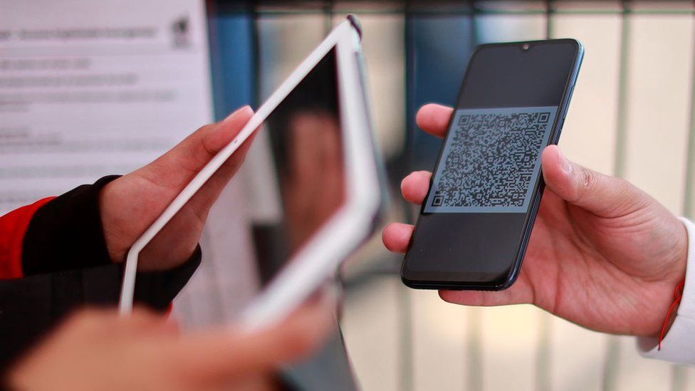 A security officer scans a mobile phone with a QR code ticket