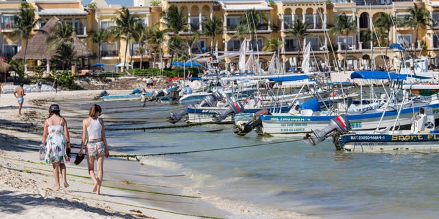 People walk along the beach in Playa del Carmen, Mexico, on Tuesday, July 11, 2017. 