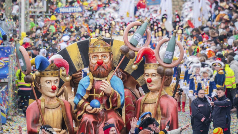 Rosenmontag in Mainz: Kaiser Barbarossa (m) mit zwei Frauen dargestellt die die Mainzer Symbole «Weck, Worscht un Woi» hochhalten.