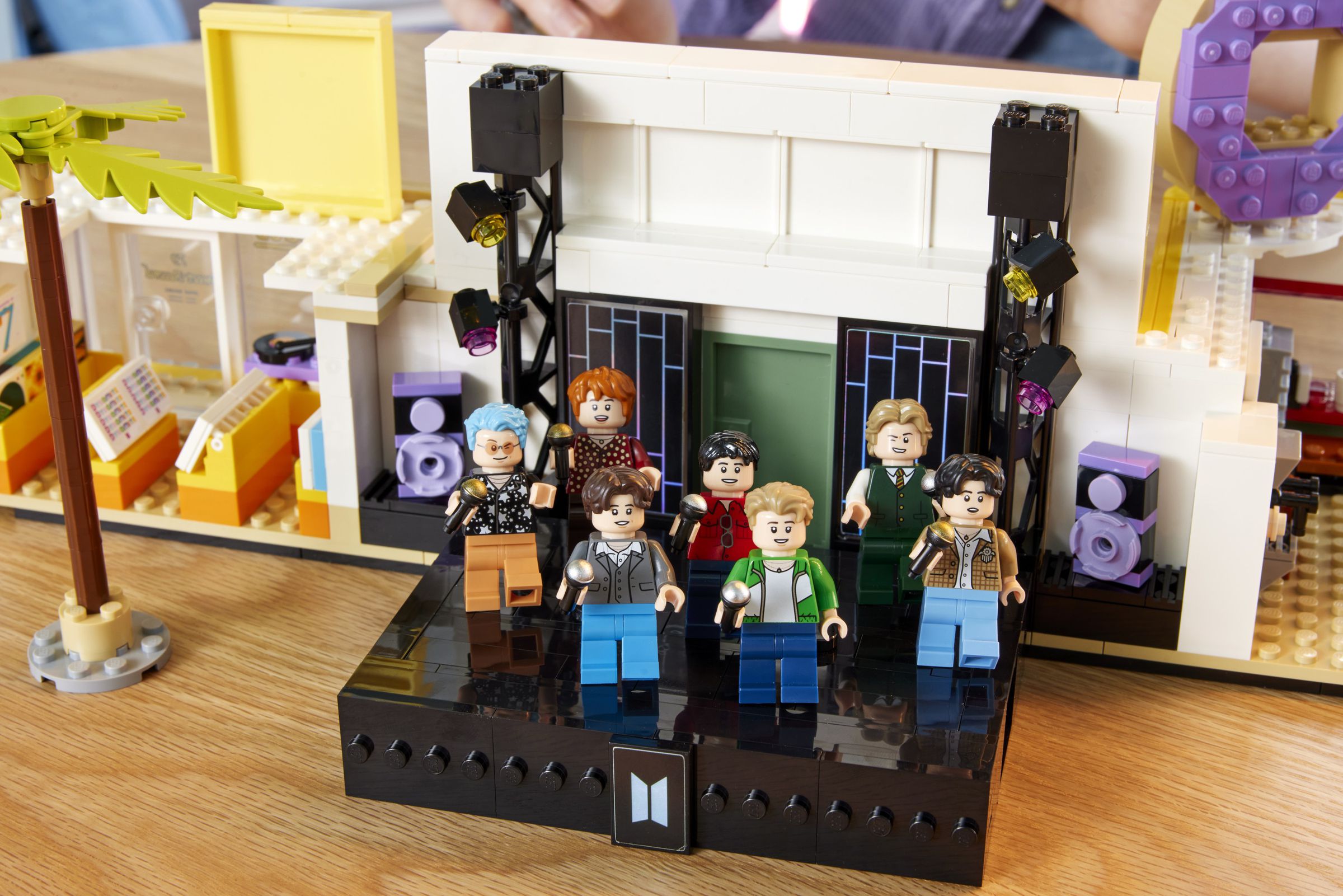 Seven BTS figurines on a black Lego stage.