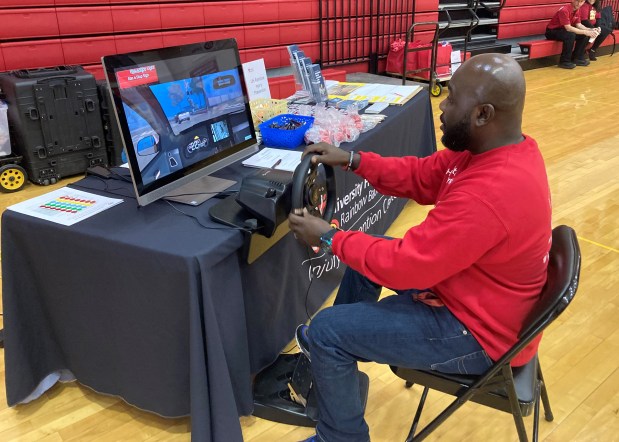 A visitor to Healthy Living at Harvey experiences the effects of distracted driving on the University Hospitals distracted and impaired driving simulator. (Bryson Durst -- The News-Herald).