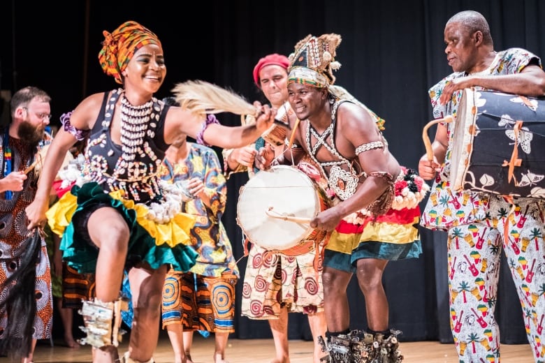 Traditional dancers and drummers in West African clothing perform on stage