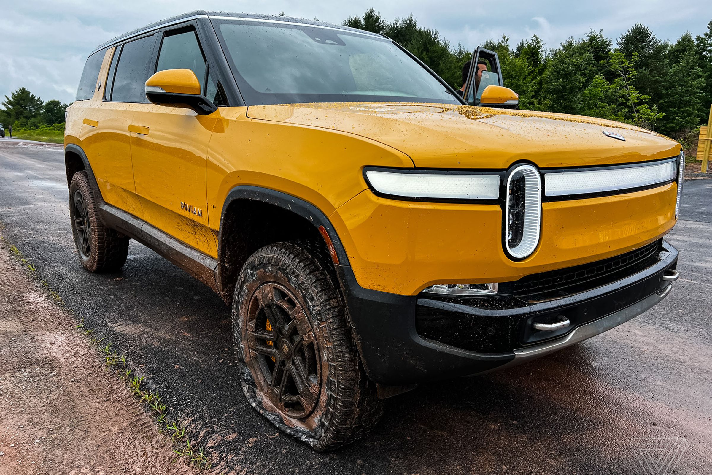 A yellow Rivian R1S with a flat front tire