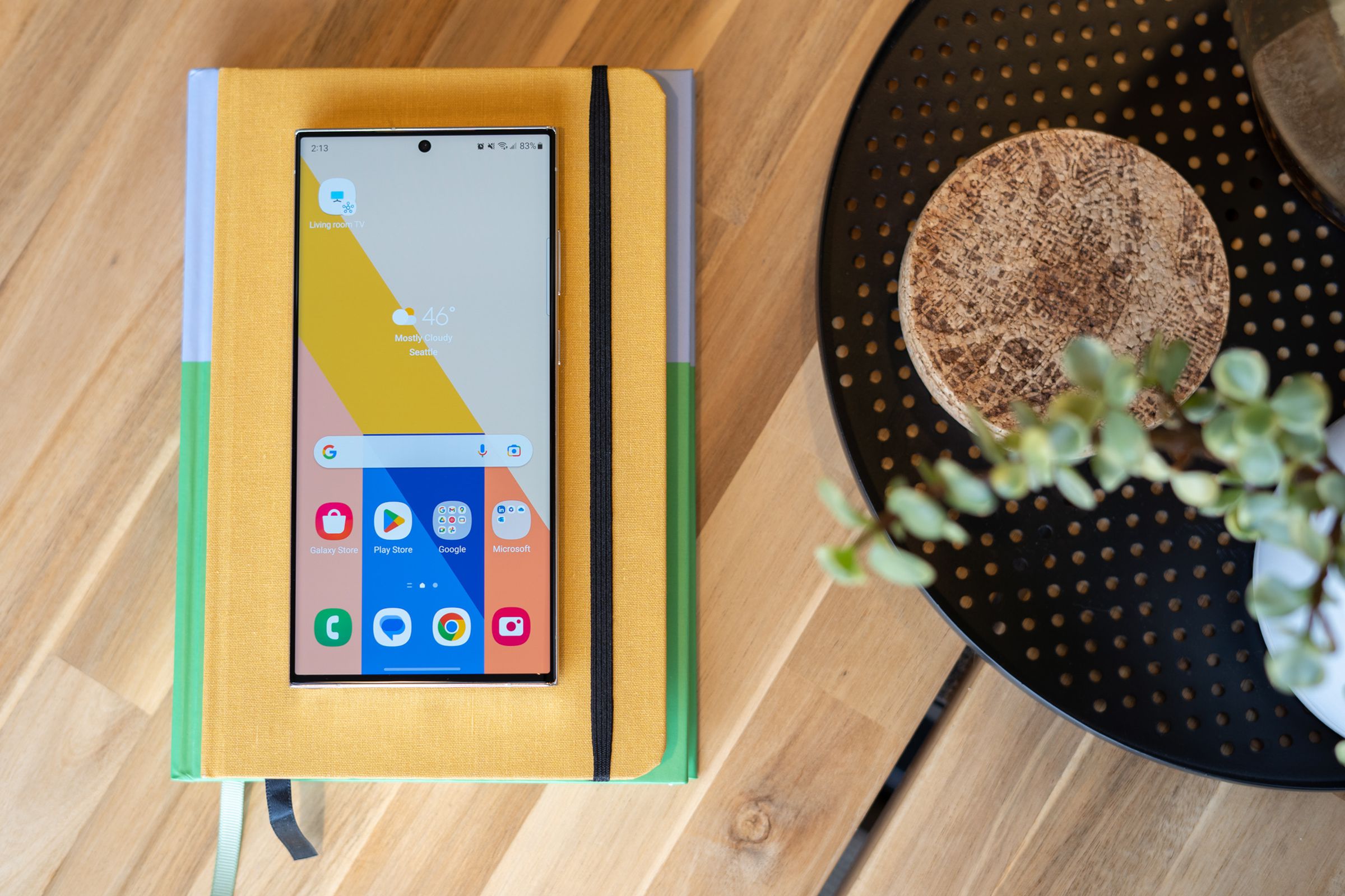 A Samsung S23 Ultra sitting on a pile of notebooks on a tabletop.