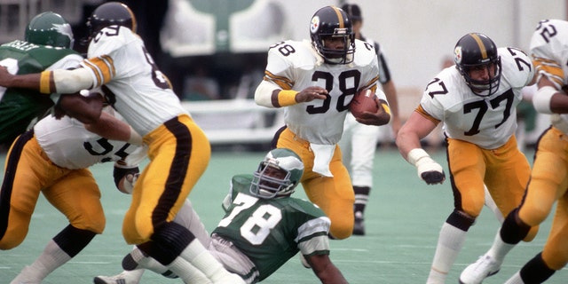 Running back Sidney Thornton, of the Pittsburgh Steelers, runs with the football against defensive lineman Carl Hairston, #78 of the Eagles, during a preseason game at Veterans Stadium on Aug. 15, 1981, in Philadelphia.