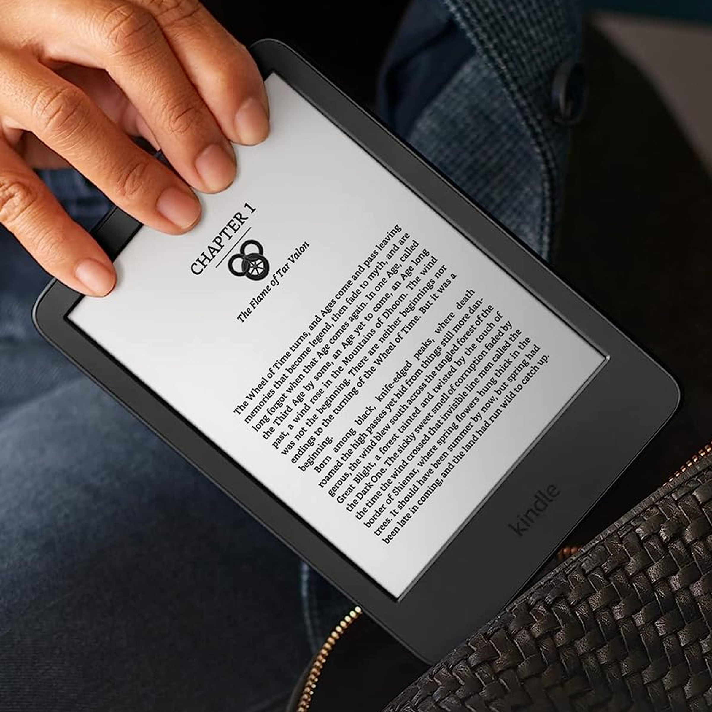 A close-up image of a hand pulling a black Kindle out of a purse.