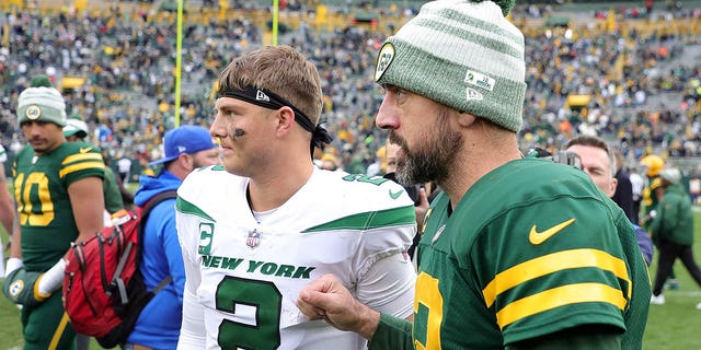 Zach Wilson, #2 of the New York Jets, speaks with Aaron Rodgers, #12 of the Green Bay Packers, following a game at Lambeau Field on October 16, 2022, in Green Bay, Wisconsin. The Jets defeated the Packers 27-10.