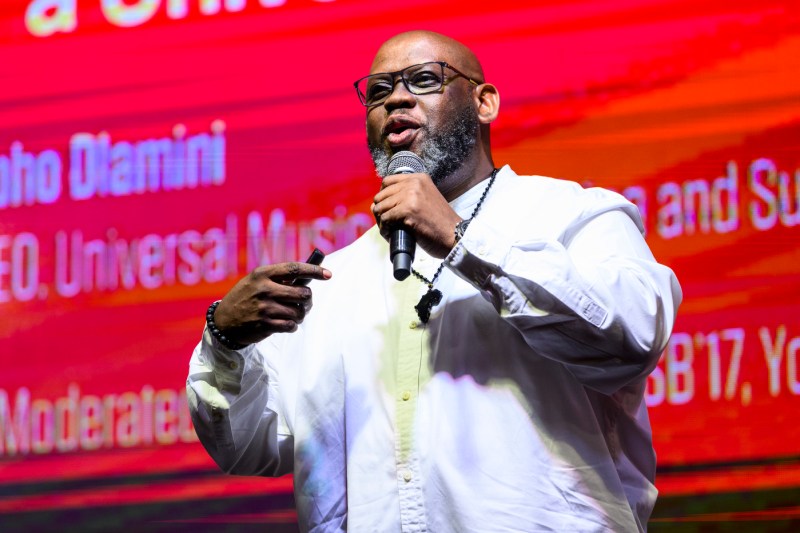 Sipho Dlamini speaking into a microphone on stage at the Global Leadership Summit