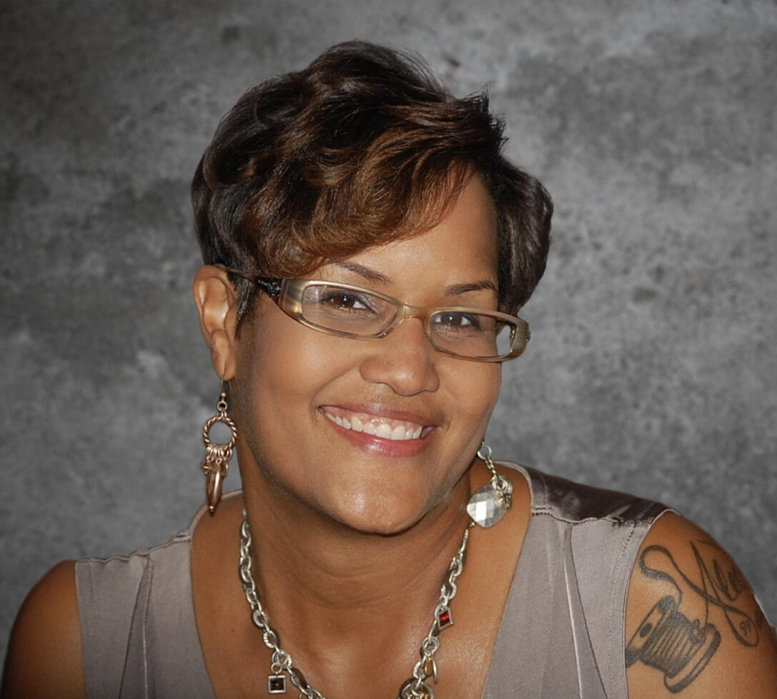 A woman wearing glasses, earrings and a necklace smiling