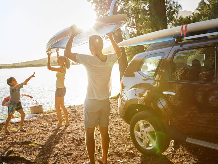 Family on a beach unloading paddle boards from their car