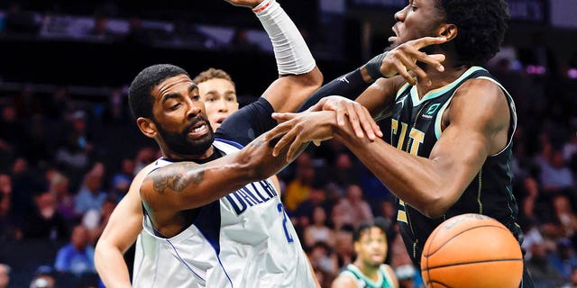 Dallas Mavericks guard Kyrie Irving and Hornets center Mark Williams battle for the ball in Charlotte, North Carolina, Sunday, March 26, 2023.