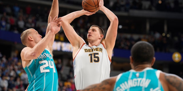 Denver Nuggets center Nikola Jokic, center, goes up for a shot between Charlotte Hornets center Mason Plumlee, left, and forward P.J. Washington in the first half of an NBA basketball game, Sunday, Dec. 18, 2022, in Denver. 