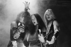 LONDON - 1st SEPTEMBER: English Thrash metal band Venom posed with candles, a cross and skull in London in September 1982. Left to Right: Tony 'Abaddon' Bray, Conrad 'Cronos' Lant, Jeffrey 'Mantas' Dunn. (Photo by Fin Costello/Redferns)