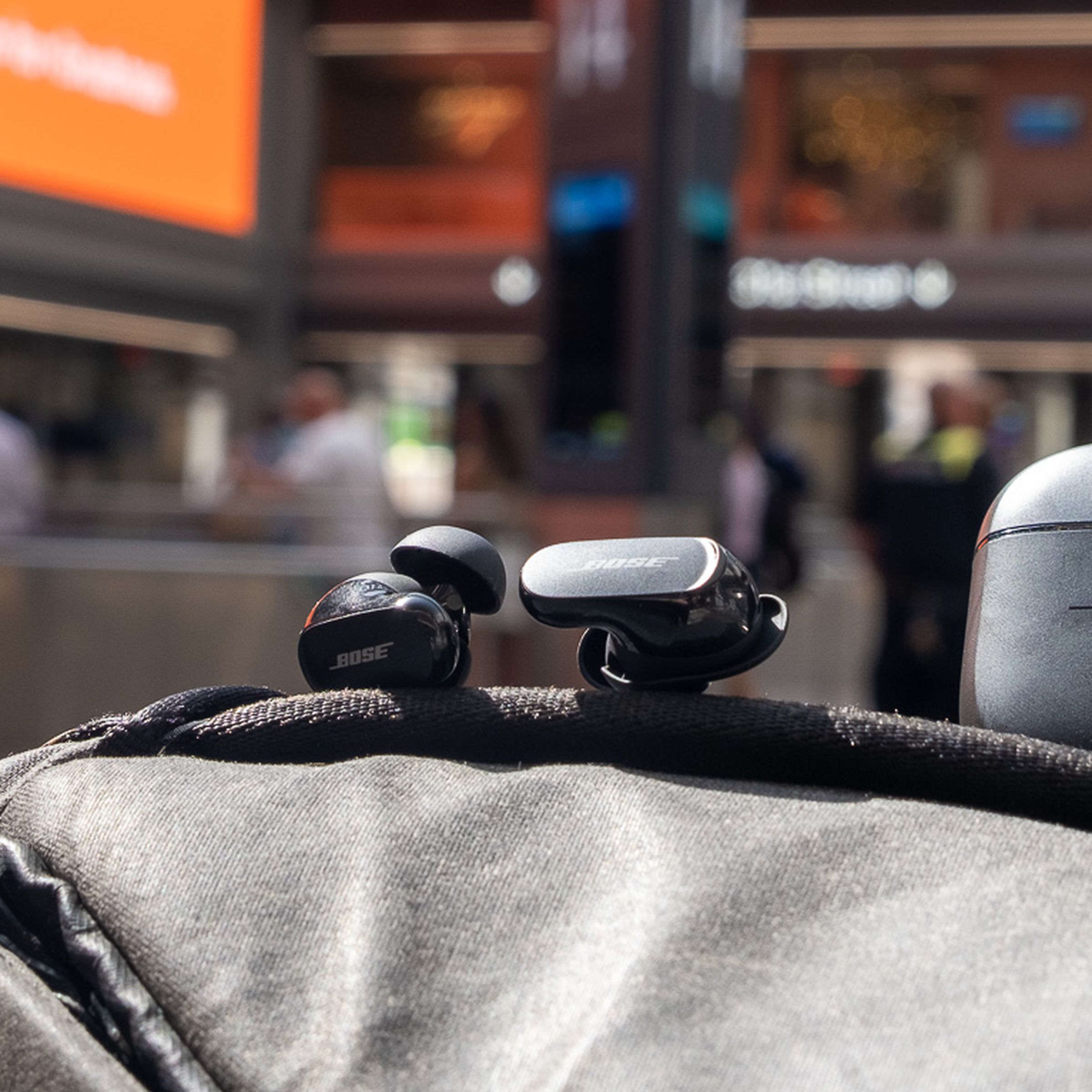 The Bose QC Earbuds II pictured on top of a backpack at Moynihan Train Hall in New York City.