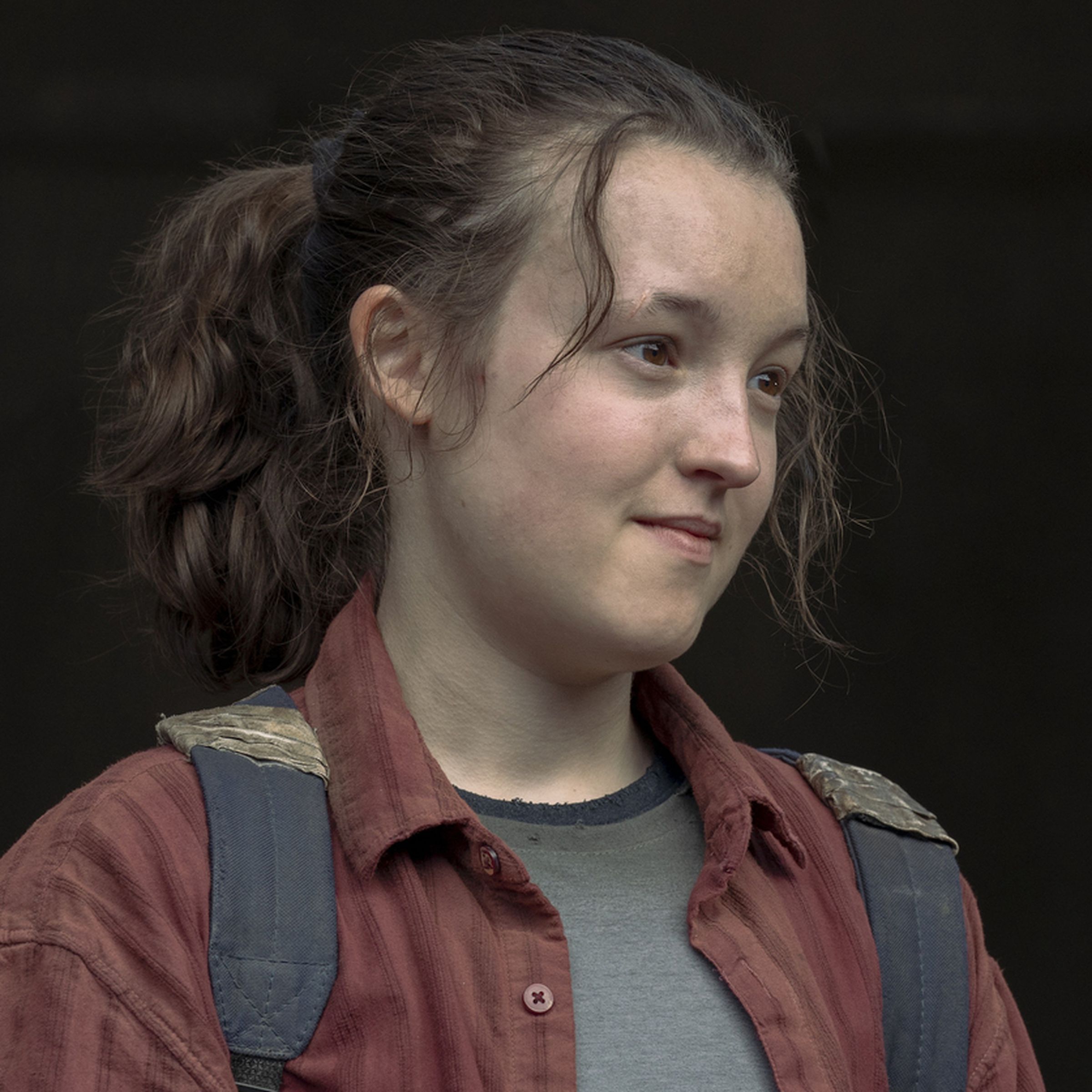 A teenager wearing a gray t-shirt under a red flannel, as well as a backpack.