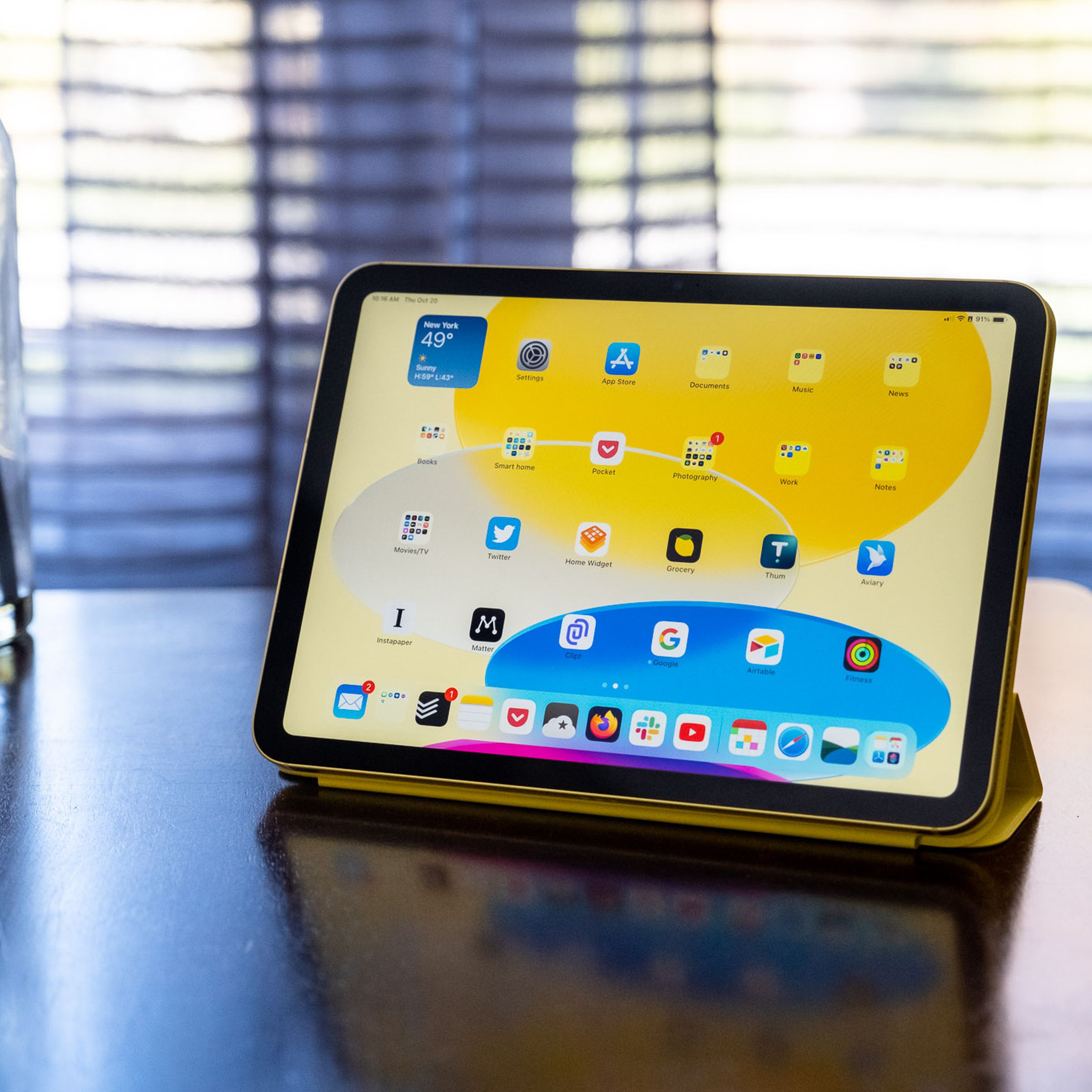 A 10th-gen iPad in an Apple Smart Folio on a wood table.