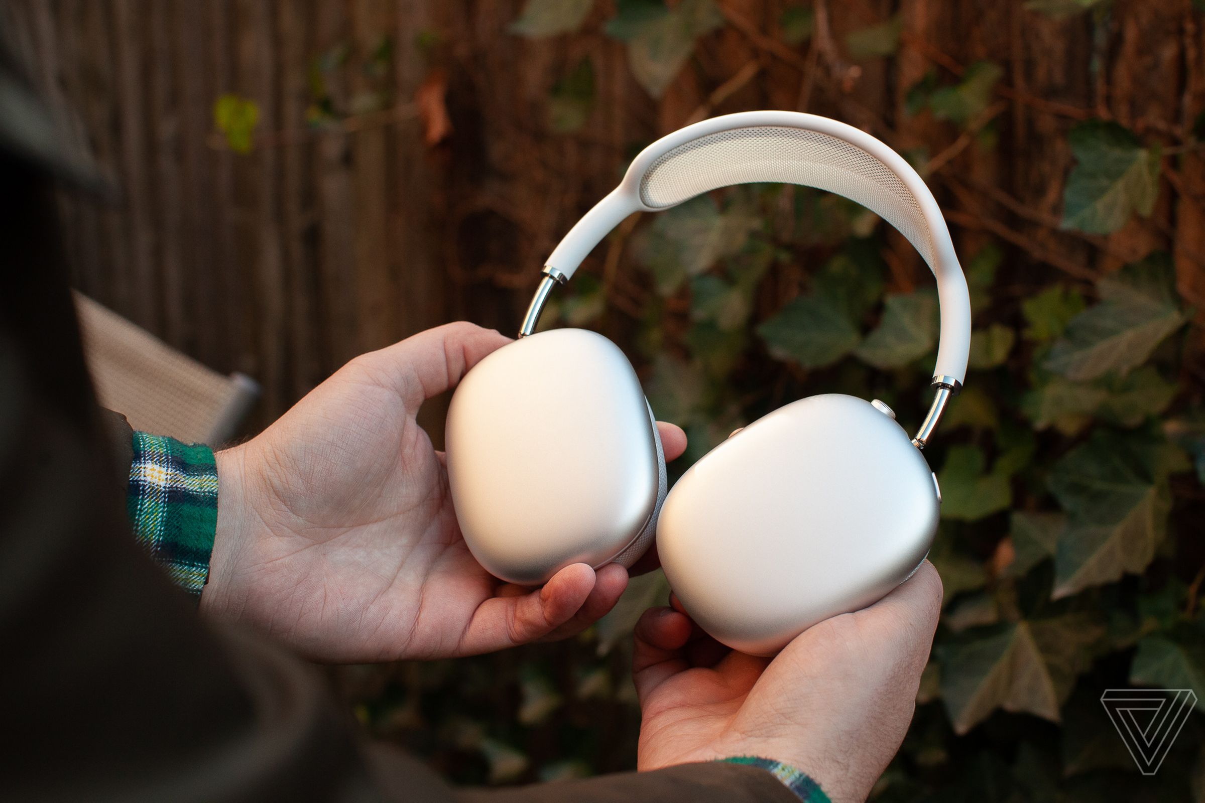 A hand holding the silver Apple AirPods Max.