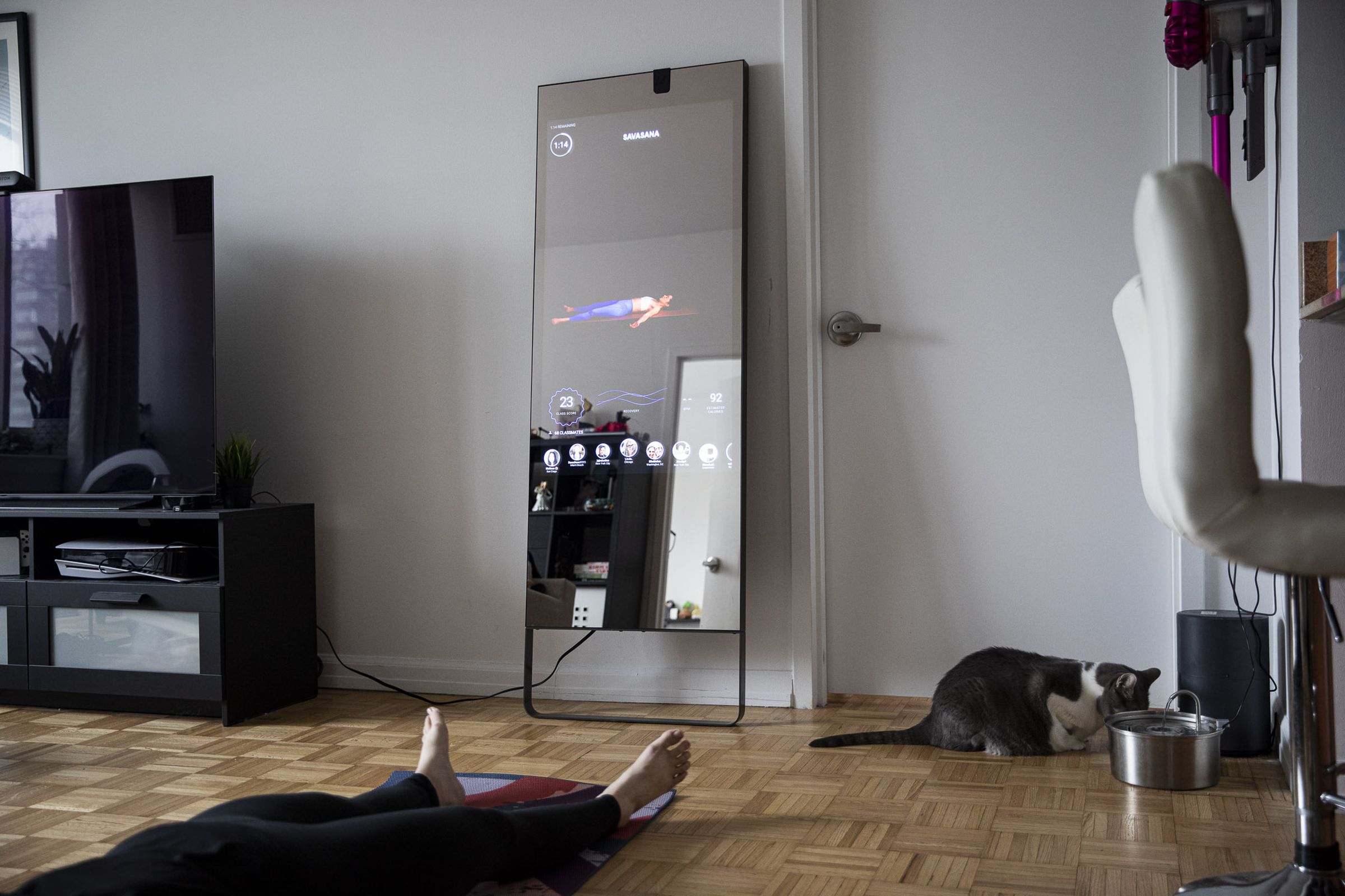 Full-length view of Mirror in living room depicting savanasa pose on screen