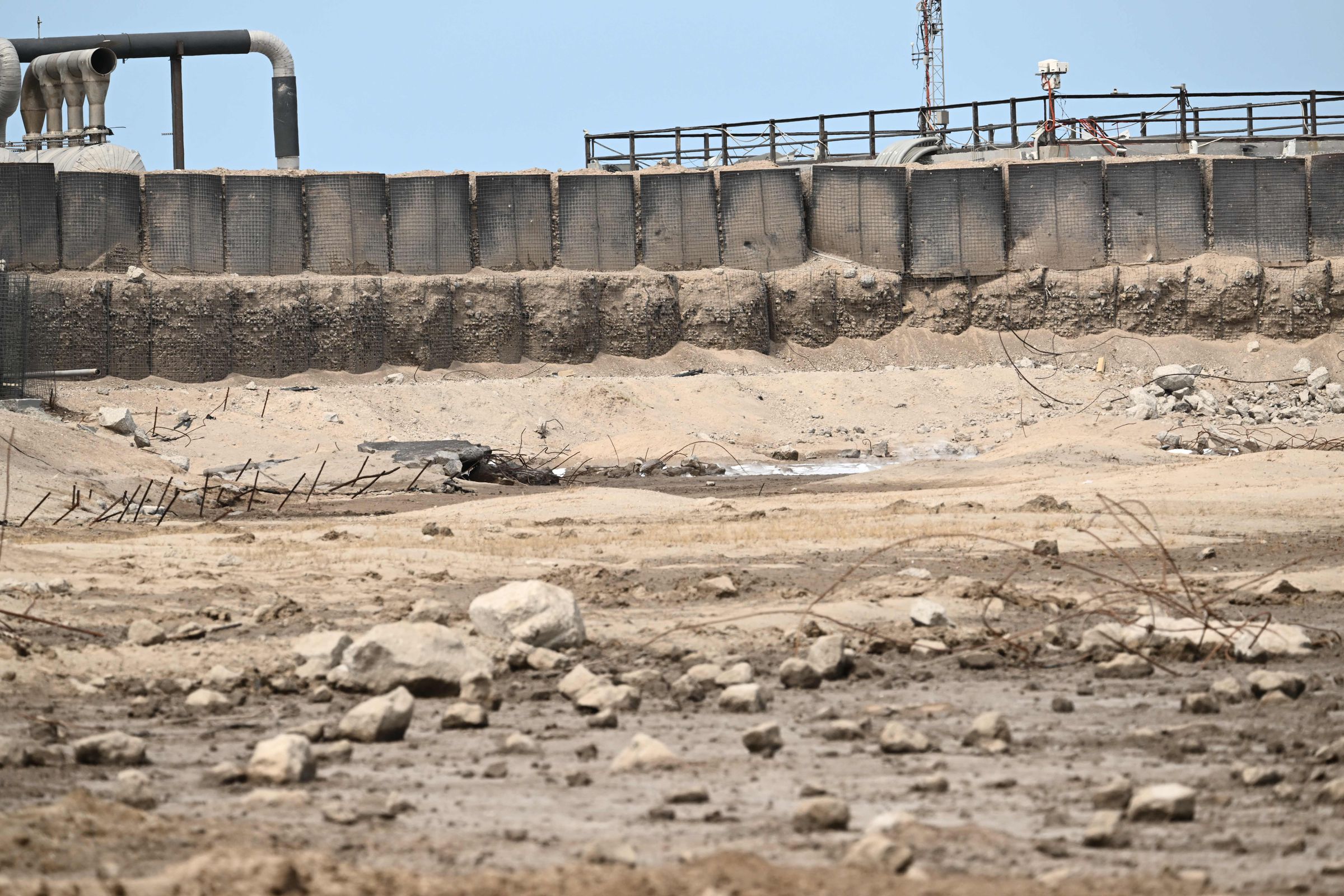 A crater in the ground littered with boulders and metal debris.