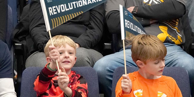 Kids holding Revolutionaries pennants