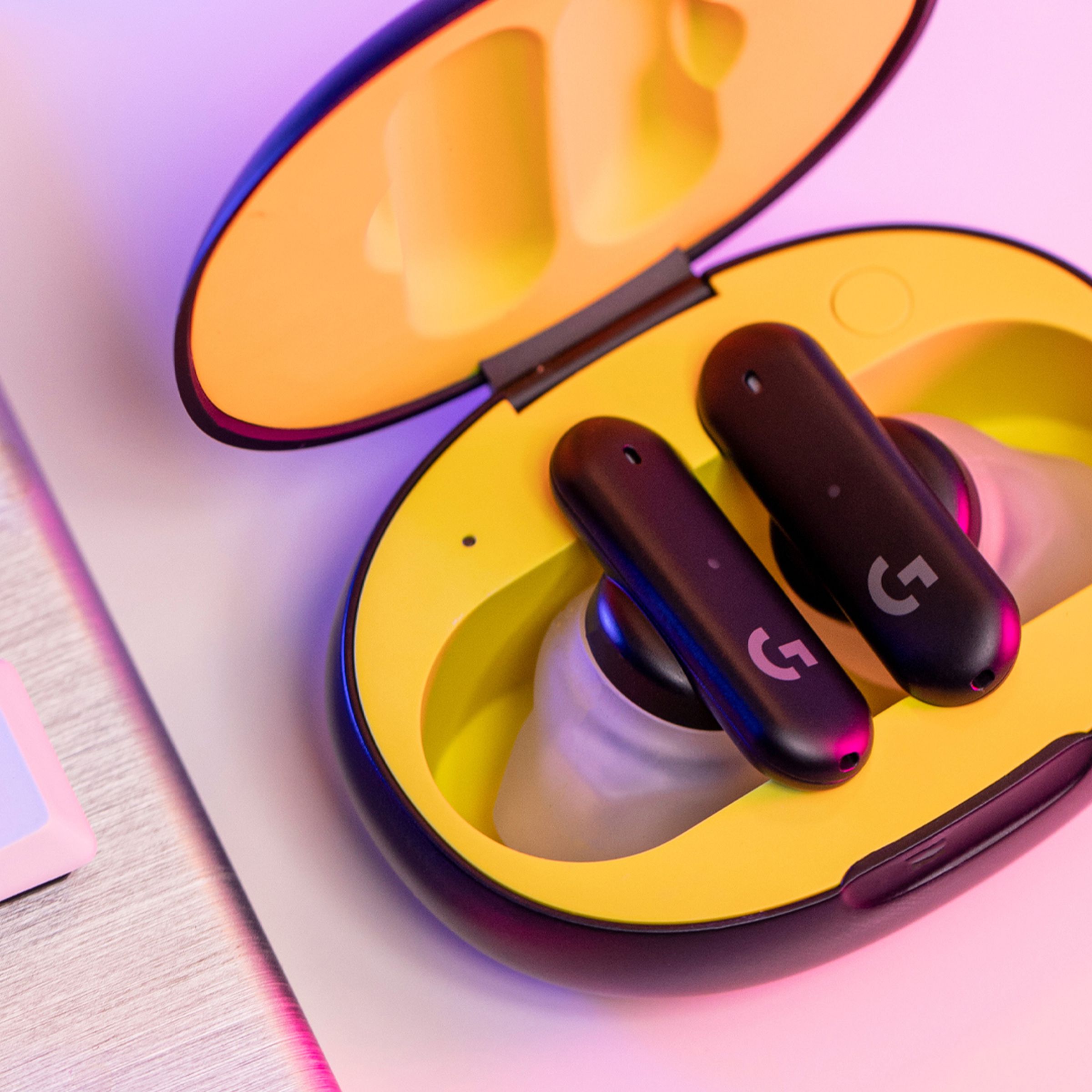 The Logitech G Fits wireless earbuds sitting in an opened yellow case.