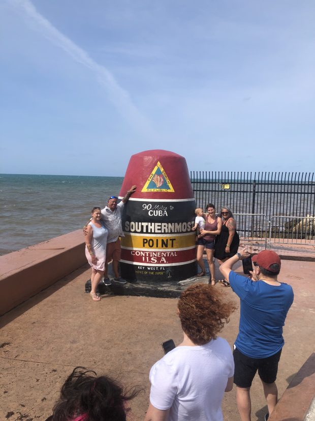 Tourists pose next to a buoy that marks the southernmost point of the continental United States. (Photo by Amy Bentley)