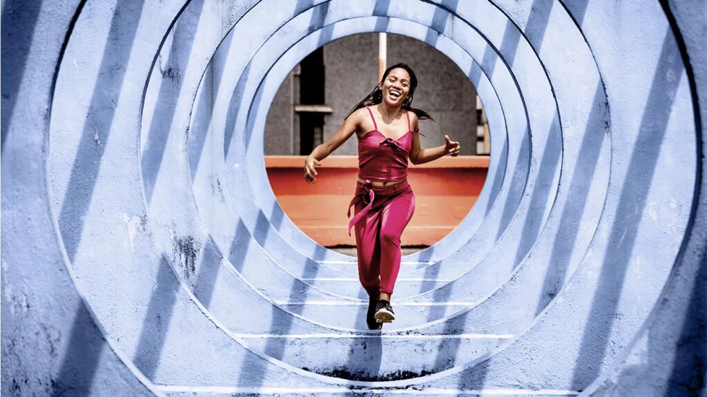 Female in pink exercise clothes runs through a blue tunnel