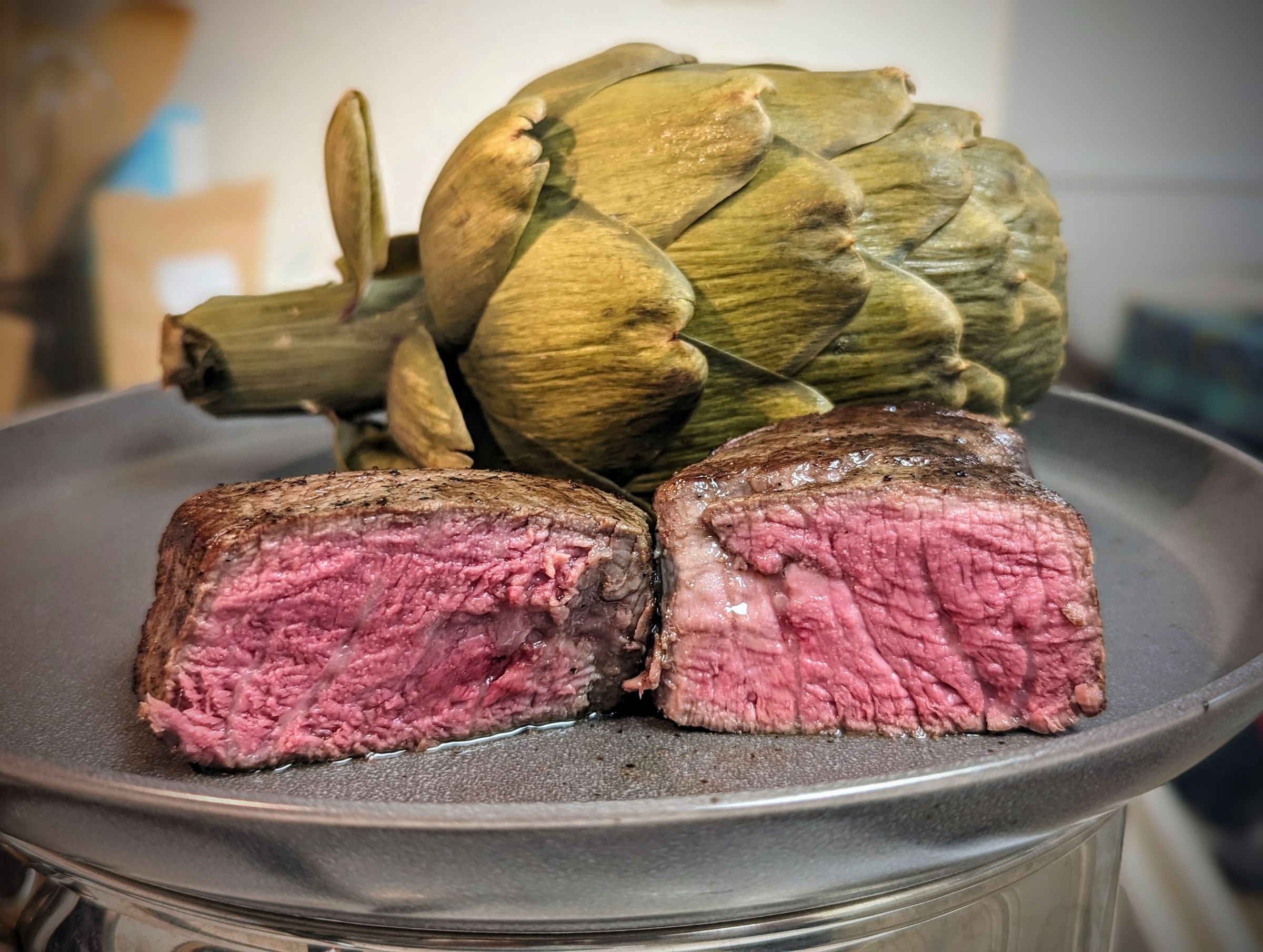 A finished steak cut in half showing an even pink throughout.