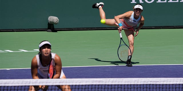 Miyu Kato serves behind Aldila Sutjiadi