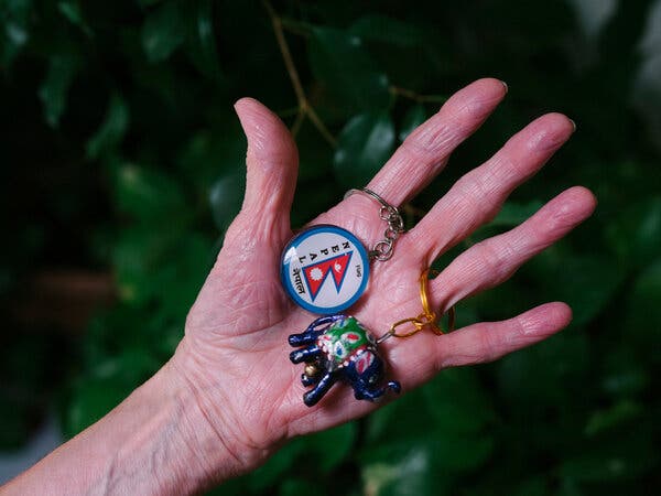 Two key rings from Nepal are displayed in the palm of a hand. 