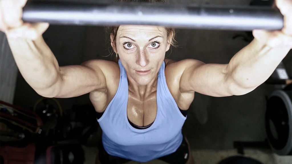 A close up from above of a woman lifting a barbell