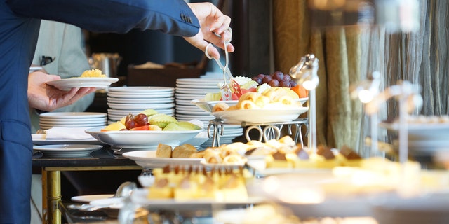 Person grabs foods at hotel buffet.