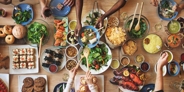 People eat at a table filled with food.