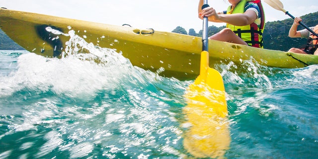 Person paddles oar while in kayak.