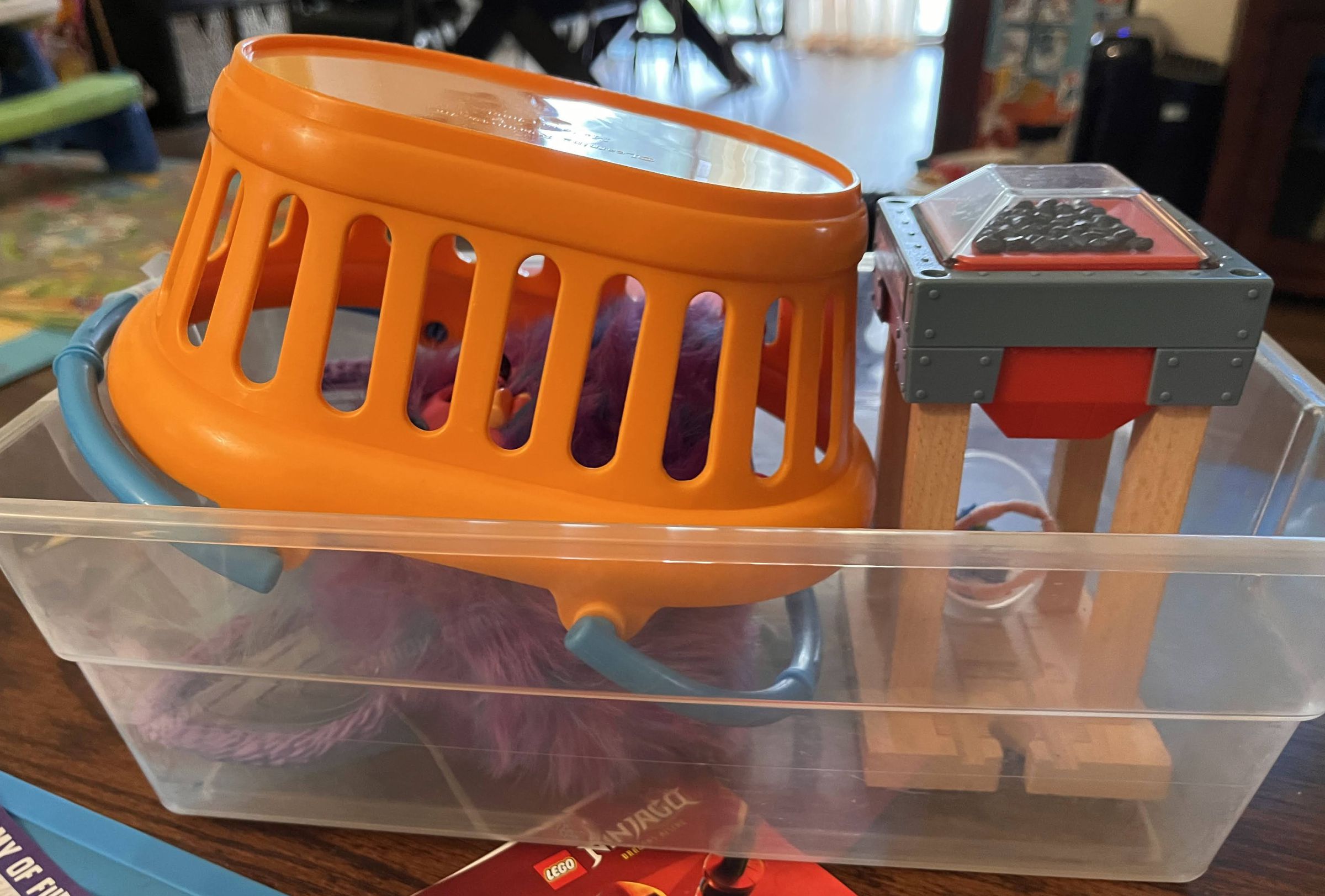 Furby underneath a kid’s shopping basket, like a cage