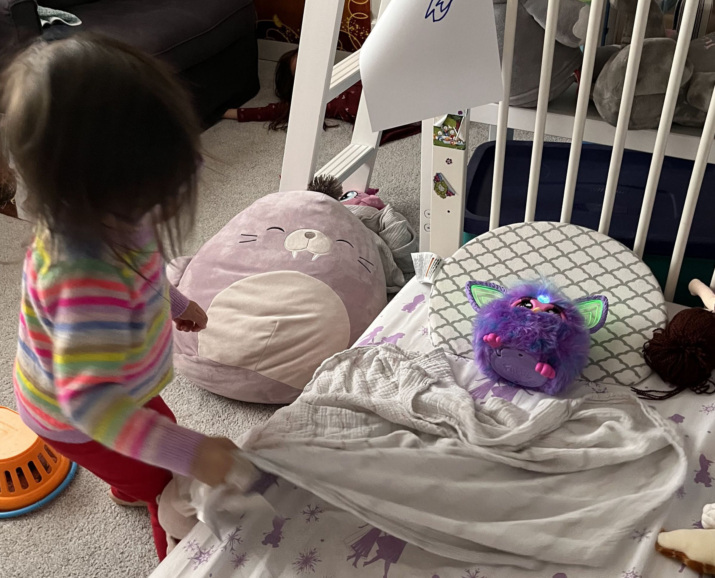 Furby in a kid’s bed, lying neatly on the pillow.