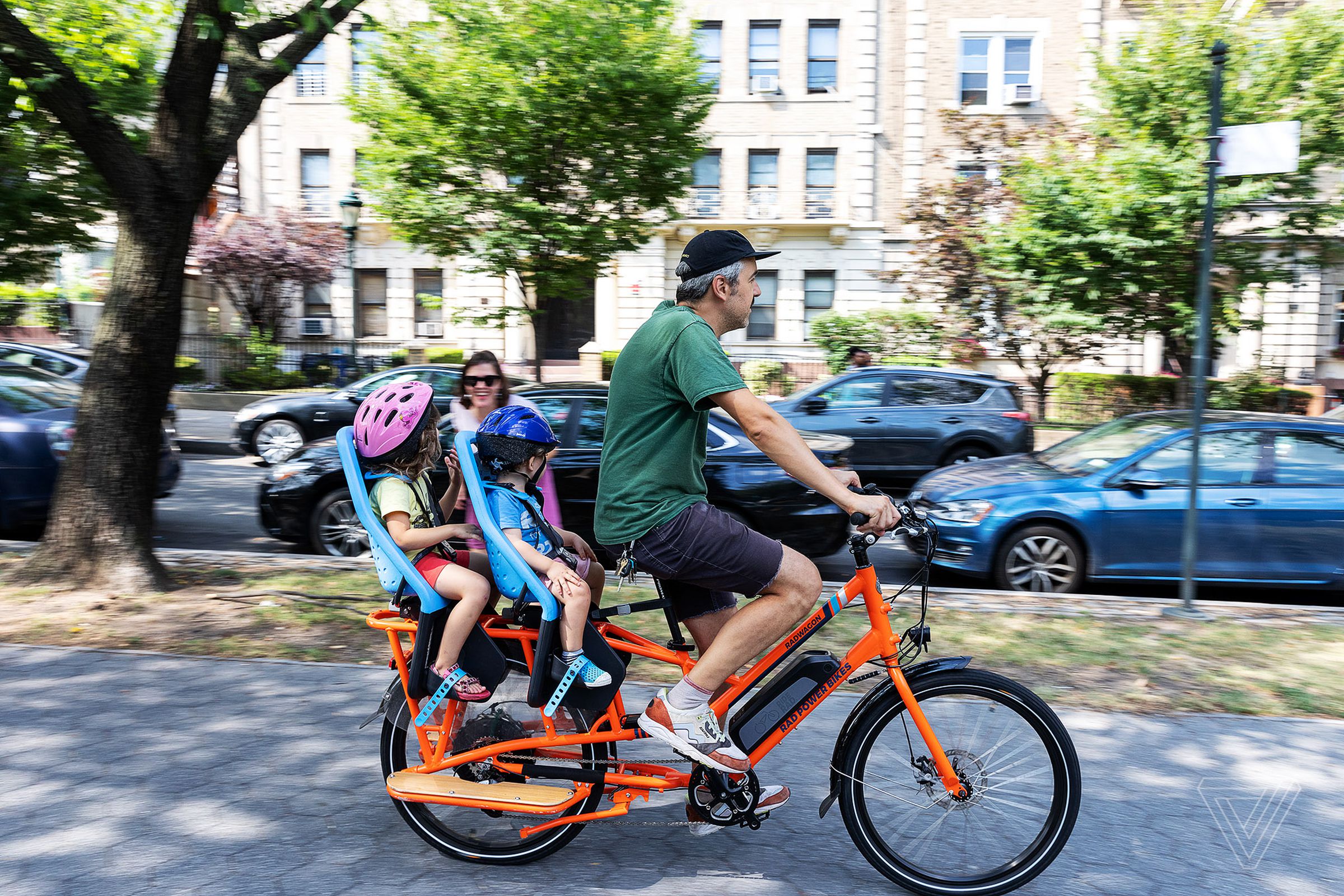 A dad riding an e-bike with two kids