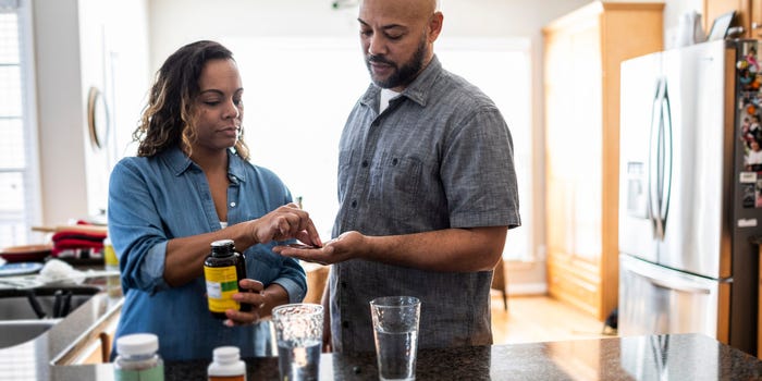 Husband and wife taking vitamins at home