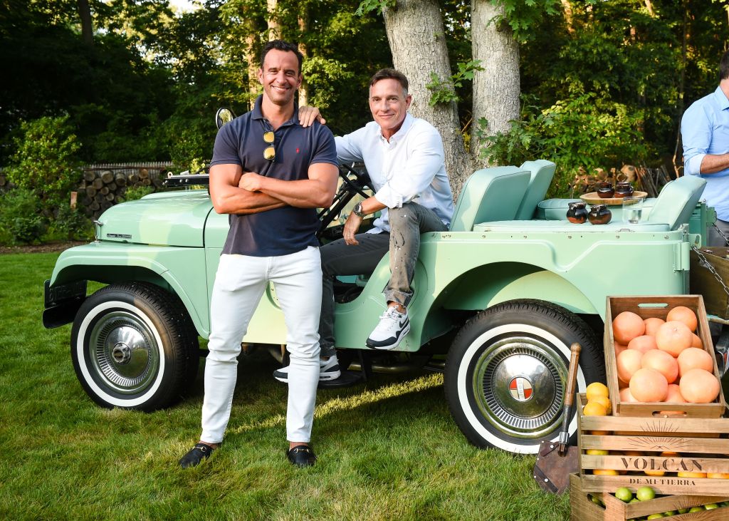 Photo of two men in green car. 