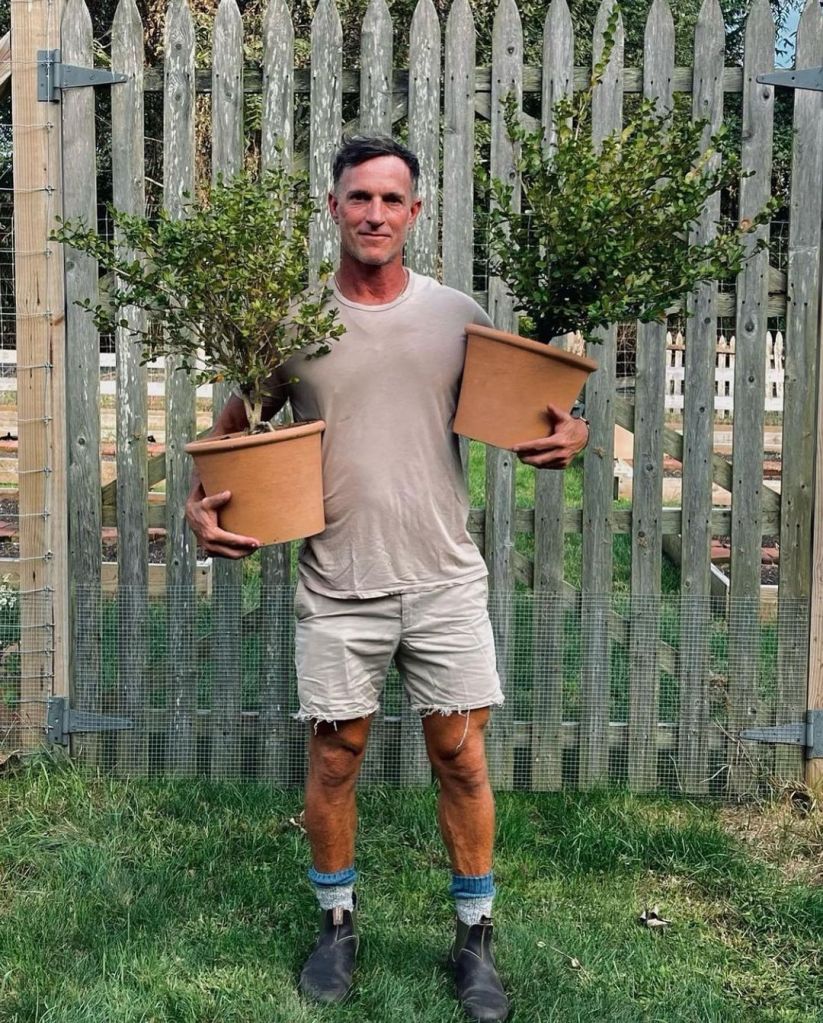 Photo of man holding two plants. 