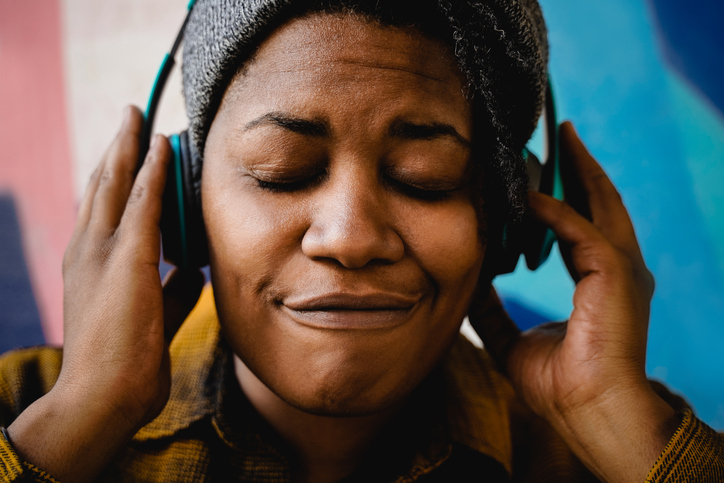 African woman listening music peaceful playlist with headphones outdoors - Urban culture lifestyle concept - Focus on face