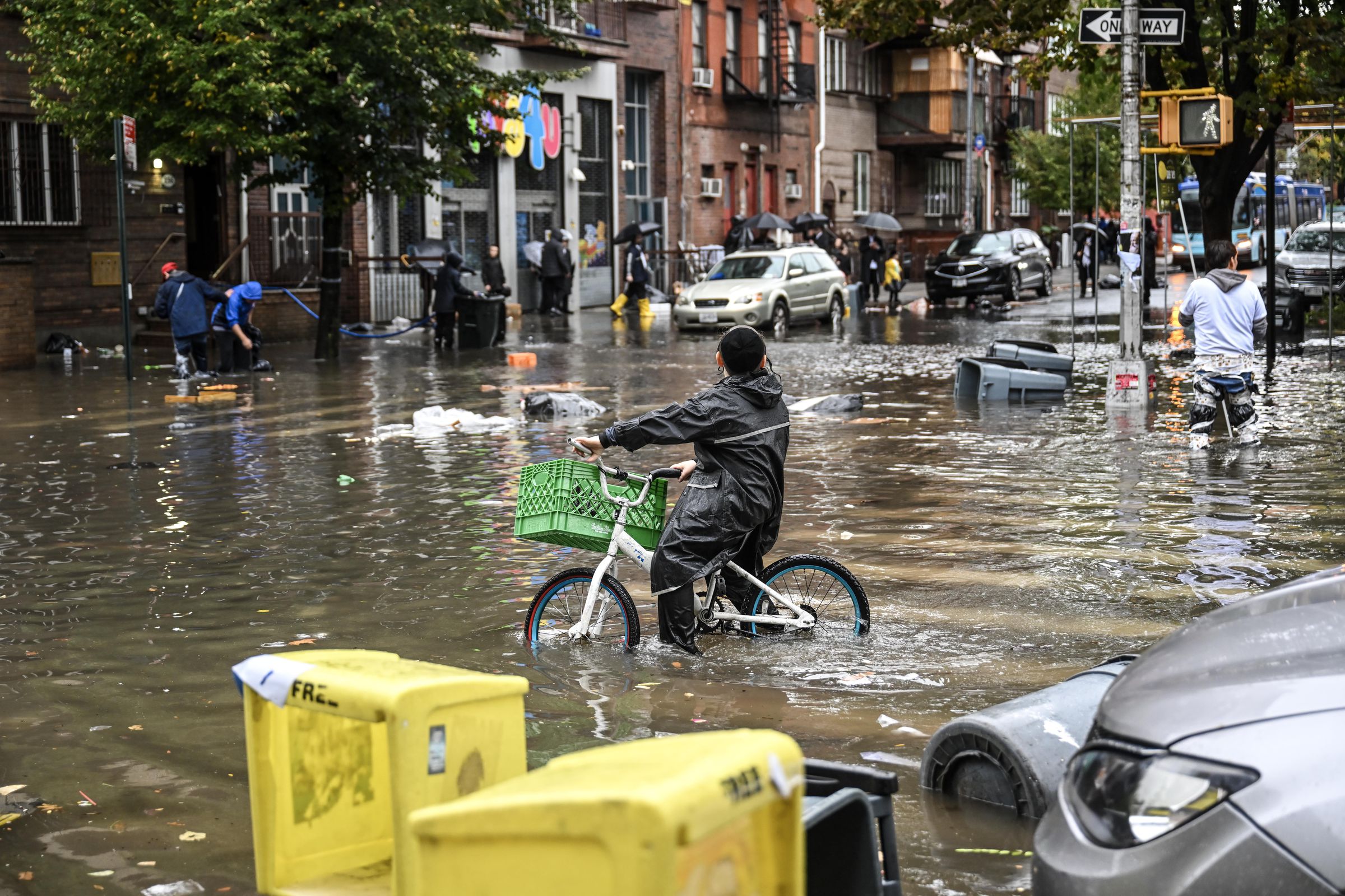 A biker and several pedestrians wade through a flooded street.