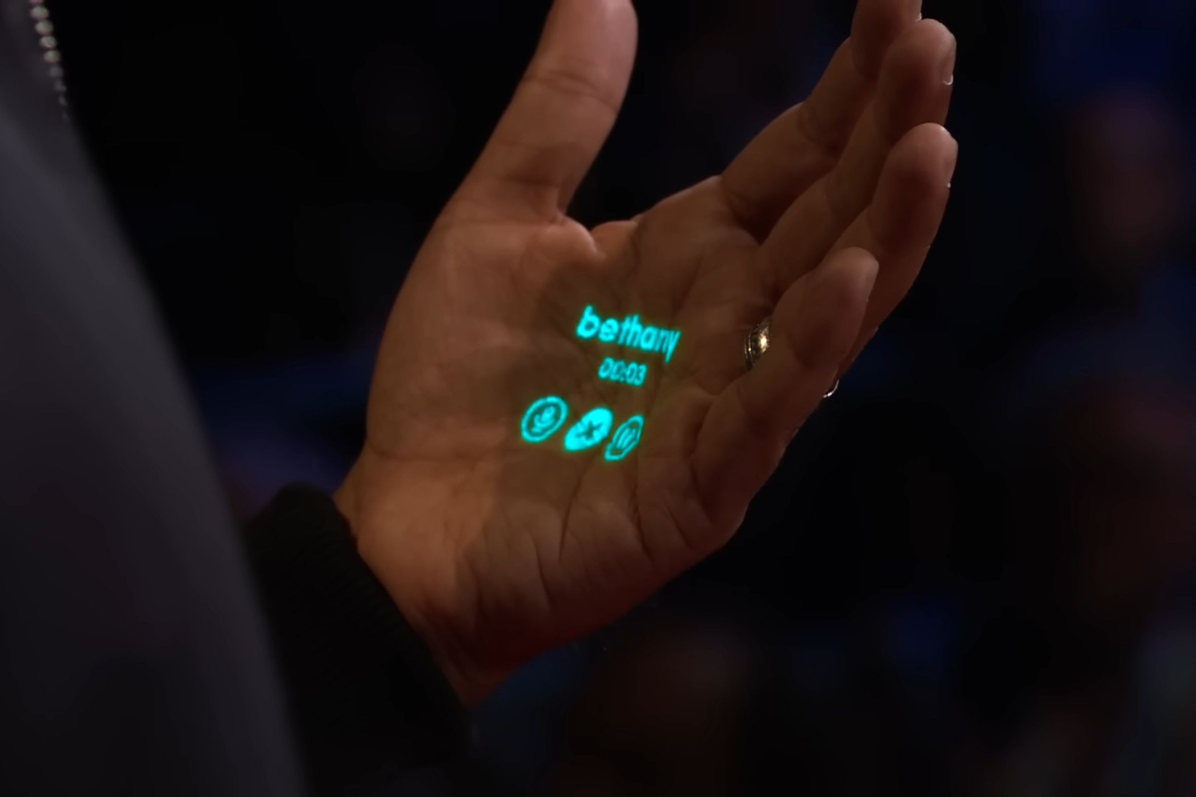 A photo from Imran Chaudhri’s TED talk about the Humane Ai Pin. The device projects details of a phone call onto his hand.