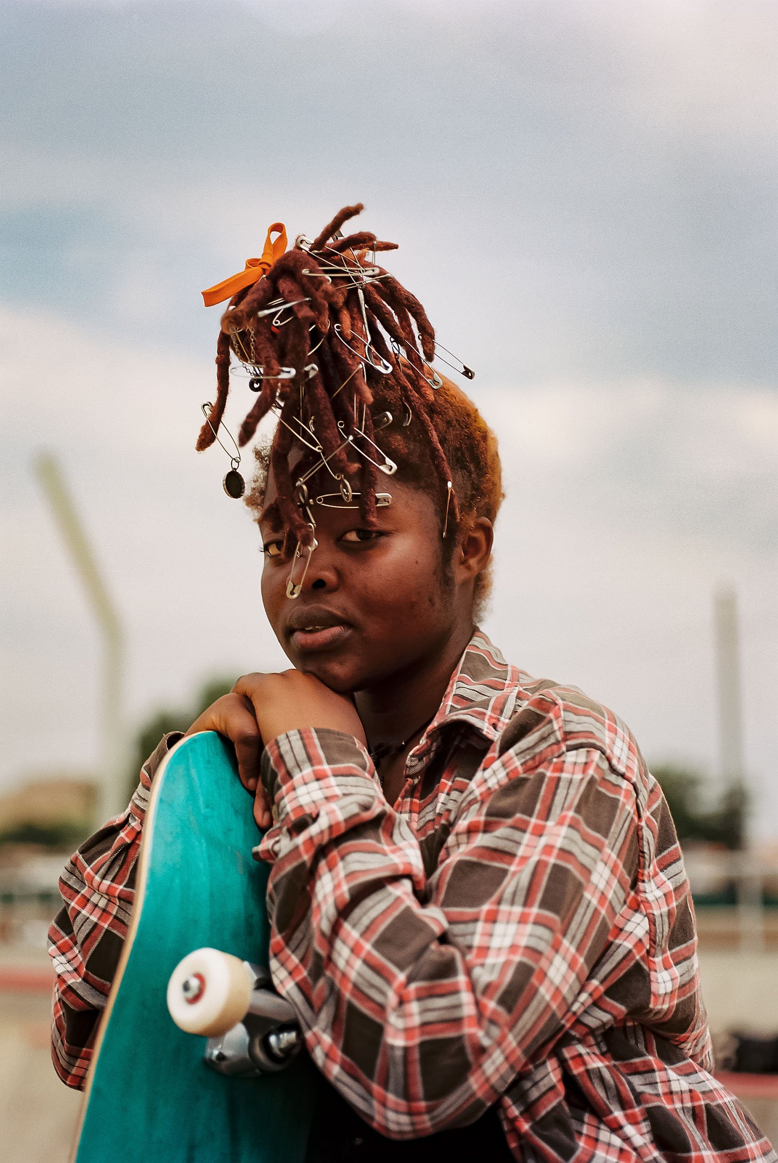 A girl leans her chin forward on a skateboard.