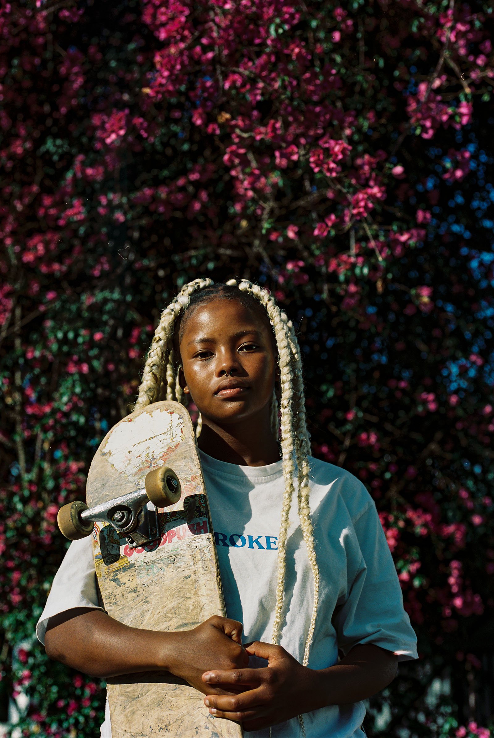 A girl stands holding a skateboard.