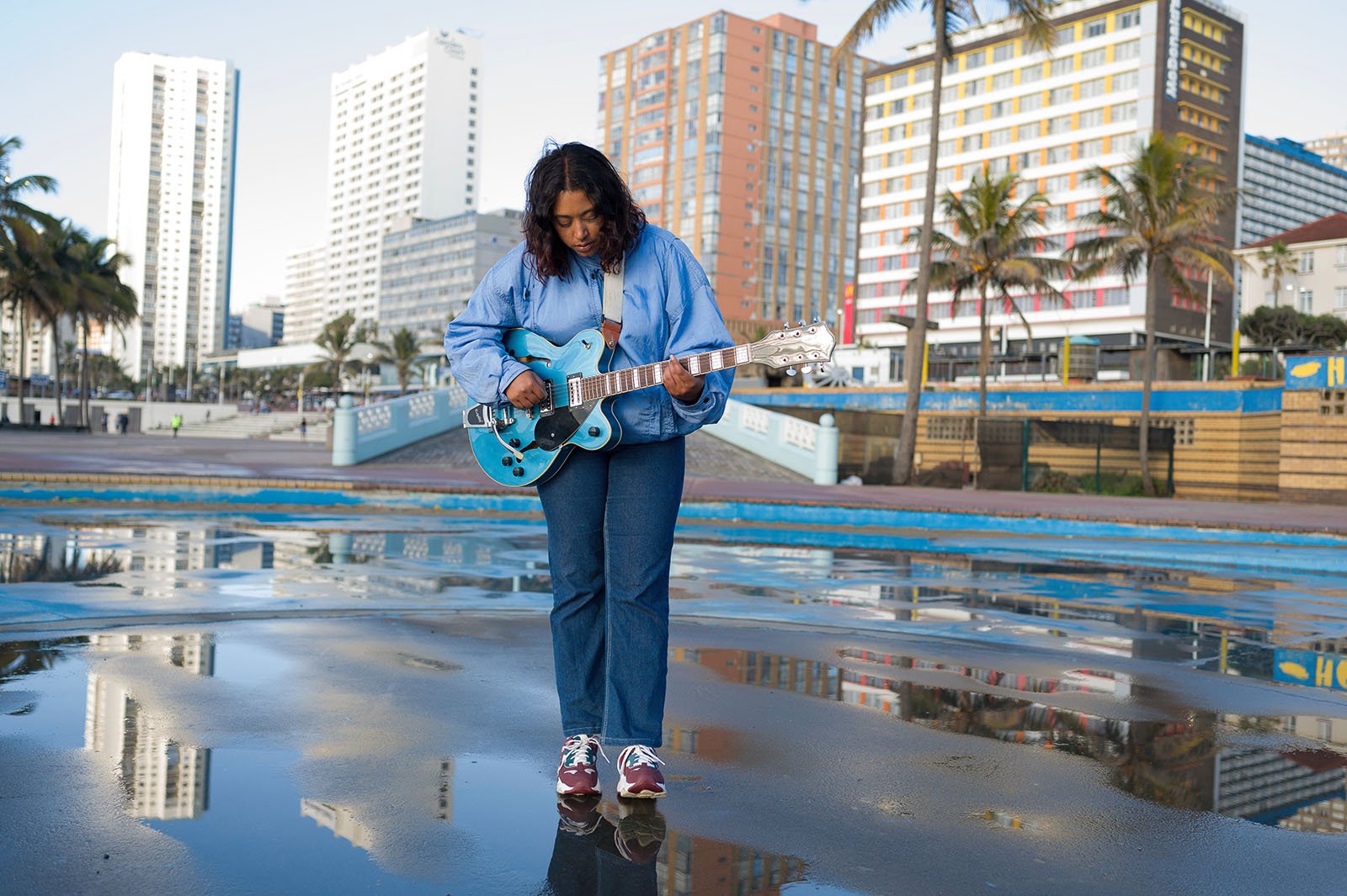 A girl plays the guitar outside.