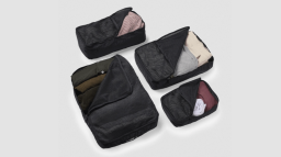 July's Packing Cells. Four black rectangular packing cells filled with rolled clothes.