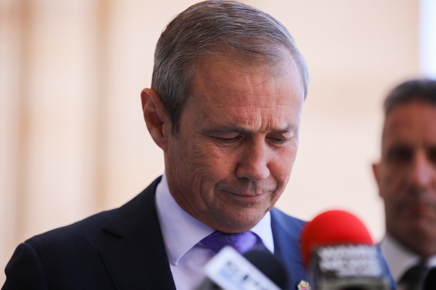 WA Premier Roger Cook speaking at a media conference with Corrective Services Minister Paul Papalia behind him.